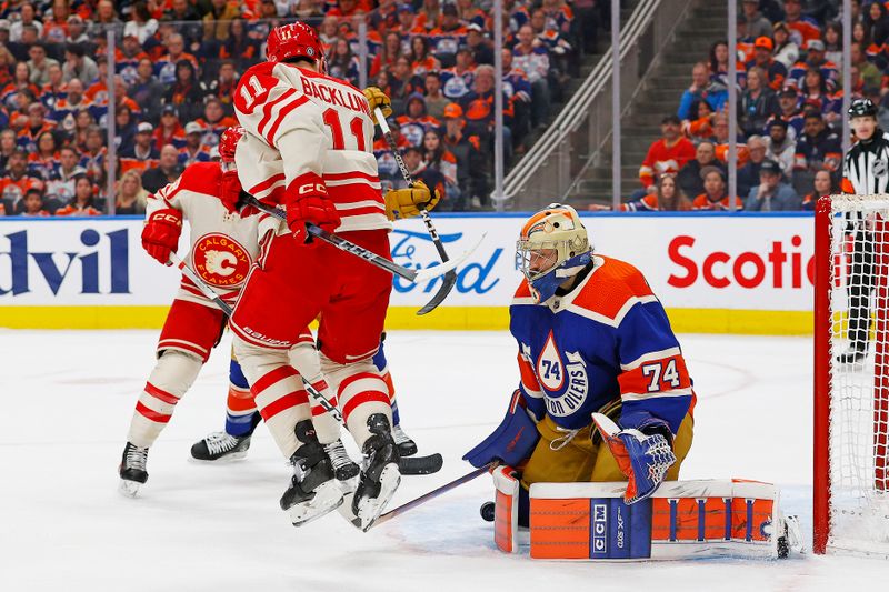 Feb 24, 2024; Edmonton, Alberta, CAN; Calgary Flames forward Michael Backlund (11) tries to deflect a shot past Edmonton Oilers goaltender Stuart Skinner (74) during the second period at Rogers Place. Mandatory Credit: Perry Nelson-USA TODAY Sports