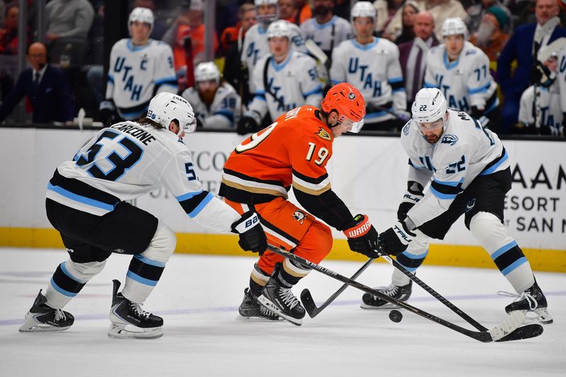 Dec 3, 2025; Anaheim, California, USA; Anaheim Ducks right wing Troy Terry (19) moves the puck against Utah Mammoth left wing Michael Carcone (53) and center Jack McBain (22) during the first period at Honda Center. Mandatory Credit: Gary A. Vasquez-Imagn Images