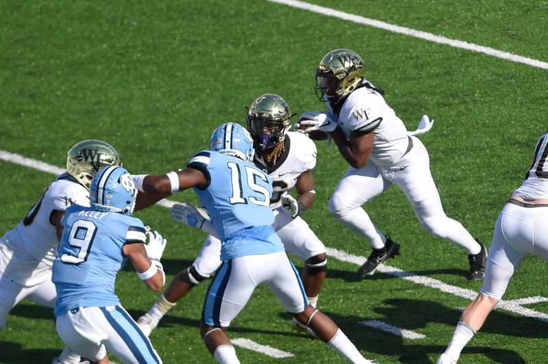 Nov 14, 2020; Chapel Hill, North Carolina, USA; Wake Forest Demon Deacons running back Kenneth Walker III (9) runs for  atouchdown as North Carolina Tar Heels defensive backs Cam'Ron Kelly (9) and  DeAndre Hollins (15) defend in the first quarter at Kenan Memorial Stadium. Mandatory Credit: Bob Donnan-USA TODAY Sports