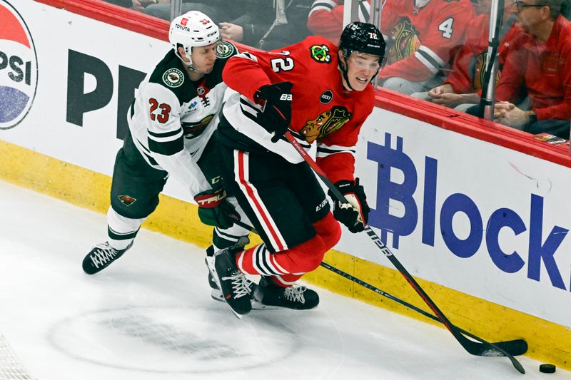 Apr 7, 2024; Chicago, Illinois, USA;  Chicago Blackhawks defenseman Alex Vlasic (72) and Minnesota Wild center Marco Rossi (23) chase the puck during the first period at United Center. Mandatory Credit: Matt Marton-USA TODAY Sports