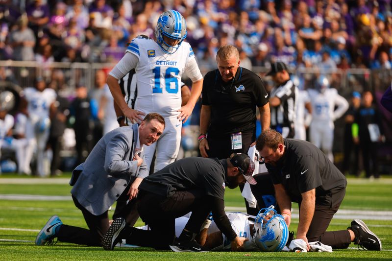 Detroit Lions running back David Montgomery (5) is looked at by medical staff after being injured against the Minnesota Vikings as quarterback Jared Goff (16) looks on during the first half of an NFL football game Sunday, Oct. 20, 2024, in Minneapolis. (AP Photo/Bruce Kluckhohn)