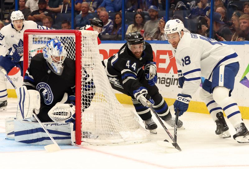 Apr 17, 2024; Tampa, Florida, USA; Toronto Maple Leafs center Noah Gregor (18) shoots as Tampa Bay Lightning defenseman Calvin de Haan (44) and goaltender Matt Tomkins (90) defend during the second period at Amalie Arena. Mandatory Credit: Kim Klement Neitzel-USA TODAY Sports