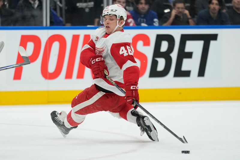 Nov 8, 2024; Toronto, Ontario, CAN; Detroit Red Wings forward Jonatan Berggren (48) reaches back to try and control a puck against the Toronto Maple Leafs during the second period at Scotiabank Arena. Mandatory Credit: John E. Sokolowski-Imagn Images