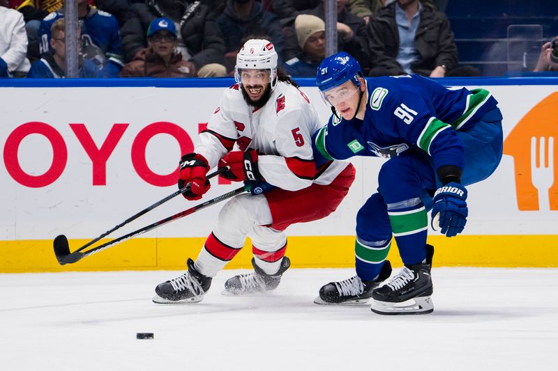 Dec 9, 2023; Vancouver, British Columbia, CAN; Vancouver Canucks defenseman Nikita Zadorov (91) defends against Carolina Hurricanes defenseman Jalen Chatfield (5) in the second period at Rogers Arena. Mandatory Credit: Bob Frid-USA TODAY Sports