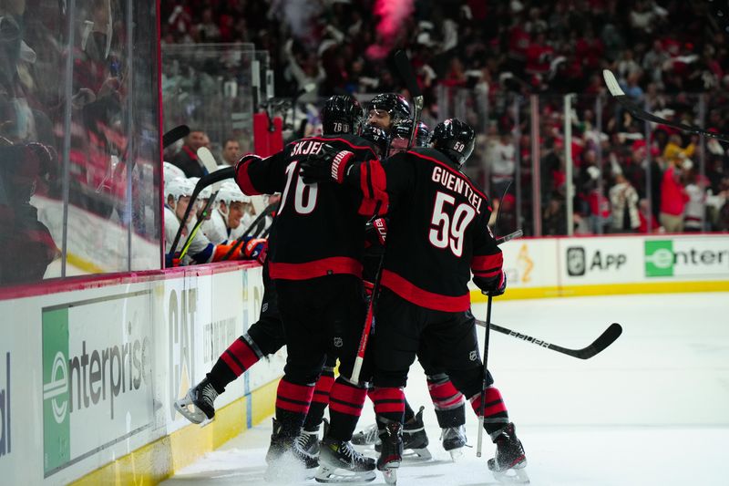 Apr 22, 2024; Raleigh, North Carolina, USA; Carolina Hurricanes center Sebastian Aho (20) celebrates his goal with defenseman Brady Skjei (76), center Jake Guentzel (59) and defenseman Brent Burns (8) against the New York Islanders during the third period in game two of the first round of the 2024 Stanley Cup Playoffs at PNC Arena. Mandatory Credit: James Guillory-USA TODAY Sports