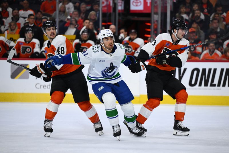 Oct 19, 2024; Philadelphia, Pennsylvania, USA; Vancouver Canucks left wing Kiefer Sherwood (44) skates between Philadelphia Flyers center Morgan Frost (48) and defenseman Jamie Drysdale (9) in the first period at Wells Fargo Center. Mandatory Credit: Kyle Ross-Imagn Images