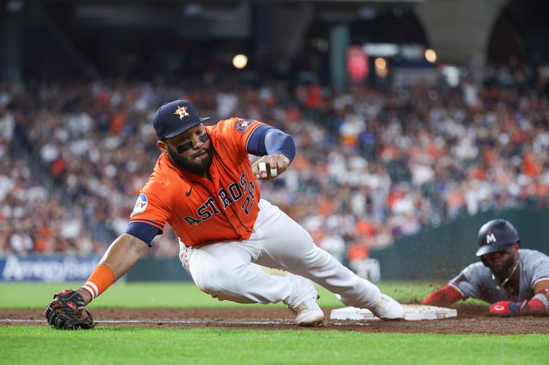 May 31, 2024; Houston, Texas, USA; Houston Astros first baseman Jon Singleton (28) attempts to field a throw as Minnesota Twins left fielder Willi Castro (50) slides back into first base on a play during the fifth inning at Minute Maid Park. Mandatory Credit: Troy Taormina-USA TODAY Sports