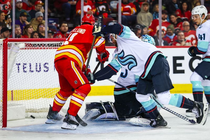 Dec 18, 2025; Calgary, Alberta, CAN; Calgary Flames center Mikael Backlund (11) scores a goal against Seattle Kraken goaltender Joey Daccord (35) during the second period at Scotiabank Saddledome. Mandatory Credit: Sergei Belski-Imagn Images