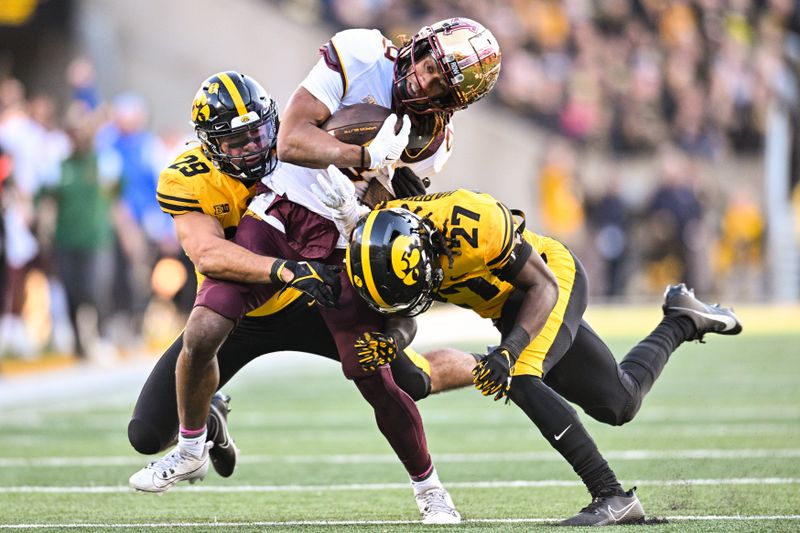 Oct 21, 2023; Iowa City, Iowa, USA; Minnesota Golden Gophers wide receiver Daniel Jackson (9) is tackled by Iowa Hawkeyes defensive back Jermari Harris (27) and defensive back Sebastian Castro (29) during the fourth quarter at Kinnick Stadium. Mandatory Credit: Jeffrey Becker-USA TODAY Sports