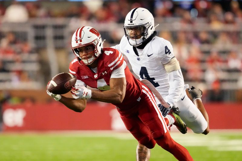 Oct 26, 2024; Madison, Wisconsin, USA;  Wisconsin Badgers wide receiver C.J. Williams (4) reaches out to catch a pass in front of Penn State Nittany Lions cornerback A.J. Harris (4) during the third quarter at Camp Randall Stadium. Mandatory Credit: Jeff Hanisch-Imagn Images