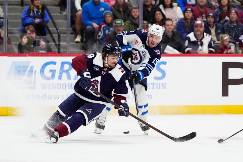 Dec 19, 2025; Denver, Colorado, USA; Winnipeg Jets center Jonathan Toews (19) shoot the puck past Colorado Avalanche defenseman Samuel Girard (49) in the first period at Ball Arena. Mandatory Credit: Ron Chenoy-Imagn Images