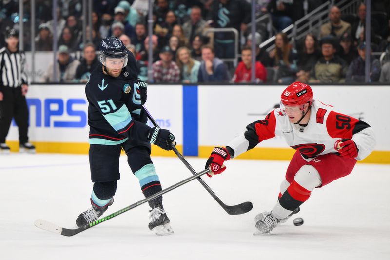 Mar 2, 2026; Seattle, Washington, USA; Seattle Kraken center Shane Wright (51) shoots the puck while defended by Carolina Hurricanes left wing Eric Robinson (50) during the second period at Climate Pledge Arena. Mandatory Credit: Steven Bisig-Imagn Images