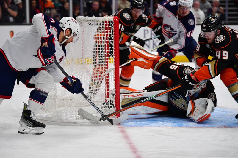 Feb 21, 2024; Anaheim, California, USA; Anaheim Ducks left wing Max Jones (49) helps goaltender John Gibson (36) defend the goal against Columbus Blue Jackets center Sean Kuraly (7) during the second period at Honda Center. Mandatory Credit: Gary A. Vasquez-USA TODAY Sports