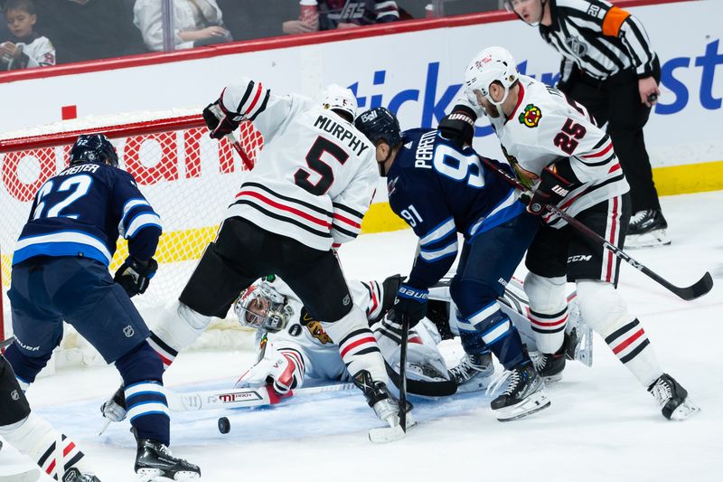 Jan 11, 2024; Winnipeg, Manitoba, CAN; Chicago Blackhawks goalie Petr Mrazek (34) makes a save as Chicago Blackhawks defenseman Connor Murphy (5), Chicago Blackhawks forward Zachary Sanfird (13), Winnipeg Jets forward Cole Perfetti (91) and Winnipeg Jets forward Nino Niederreiter (62) look for a rebound during the third period at Canada Life Centre. Mandatory Credit: Terrence Lee-USA TODAY Sports