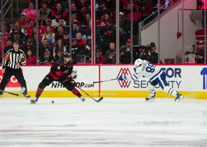 Mar 24, 2024; Raleigh, North Carolina, USA;  Toronto Maple Leafs left wing Nicholas Robertson (89) takes the puck past Carolina Hurricanes center Jack Drury (18) during the third period at PNC Arena. Mandatory Credit: James Guillory-USA TODAY Sports