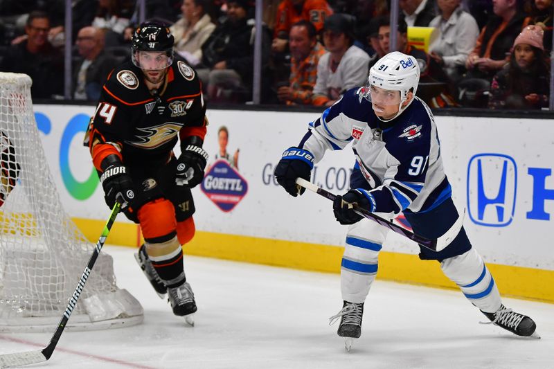 Jan 5, 2024; Anaheim, California, USA; Winnipeg Jets center Cole Perfetti (91) moves the puck ahead of Anaheim Ducks center Adam Henrique (14) during the third period at Honda Center. Mandatory Credit: Gary A. Vasquez-USA TODAY Sports