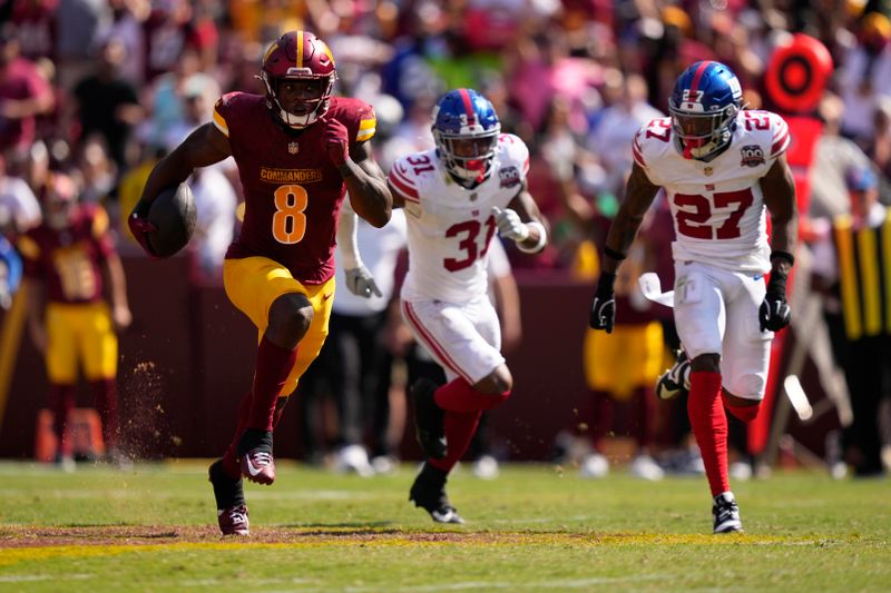 Washington Commanders running back Brian Robinson Jr. (8) runs past New York Giants safety Jason Pinnock (27) and safety Jason Pinnock (27) during the second half of an NFL football game in Landover, Md., Sunday, Sept. 15, 2024. (AP Photo/Matt Slocum)