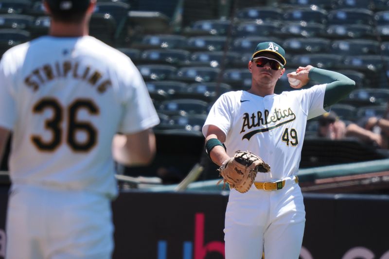 May 1, 2024; Oakland, California, USA; Oakland Athletics first baseman Ryan Noda (49) throws the ball to starting pitcher Ross Stripling (36) after a throwing error during the second inning at Oakland-Alameda County Coliseum. Mandatory Credit: Kelley L Cox-USA TODAY Sports