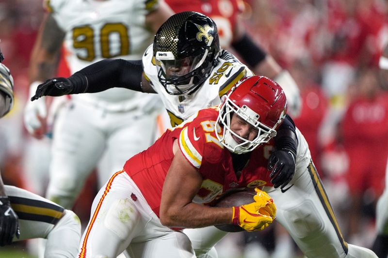 Kansas City Chiefs tight end Travis Kelce (87) catches a pass as New Orleans Saints defensive tackle Khalen Saunders (50) defends during the first half of an NFL football game Monday, Oct. 7, 2024, in Kansas City, Mo. (AP Photo/Charlie Riedel)