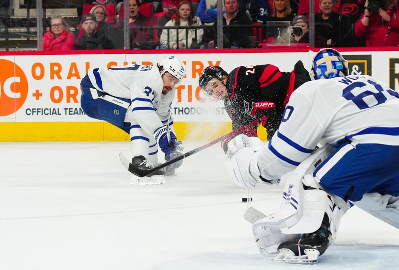 Mar 24, 2024; Raleigh, North Carolina, USA;  Toronto Maple Leafs defenseman Timothy Liljegren (37) checks Carolina Hurricanes center Seth Jarvis (24) off the puck during the third period at PNC Arena. Mandatory Credit: James Guillory-USA TODAY Sports