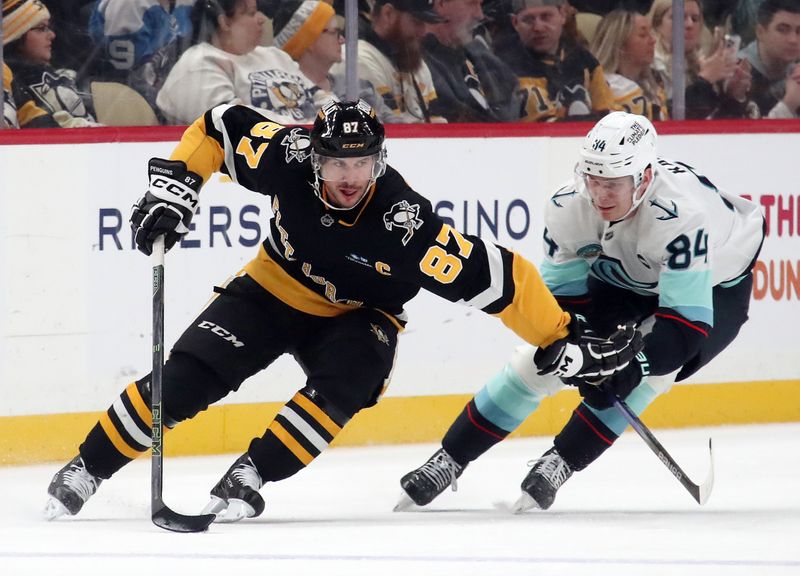 Jan 14, 2025; Pittsburgh, Pennsylvania, USA;  Pittsburgh Penguins center Sidney Crosby (87) skates with the puck against Seattle Kraken right wing Kaapo Kakko (84) during the first period at PPG Paints Arena. Mandatory Credit: Charles LeClaire-Imagn Images