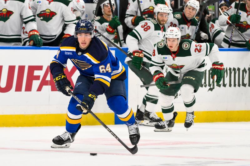 Nov 19, 2024; St. Louis, Missouri, USA;  St. Louis Blues defenseman Corey Schueneman (64) controls the puck against the Minnesota Wild during the second period at Enterprise Center. Mandatory Credit: Jeff Curry-Imagn Images