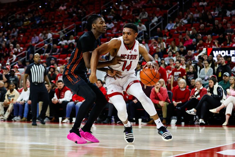 Jan 30, 2024; Raleigh, North Carolina, USA; North Carolina State Wolfpack guard Casey Morsell (14) dribbles with the ball past Miami (Fl) Hurricanes guard Wooga Poplar (5) during the first half at PNC Arena. Mandatory Credit: Jaylynn Nash-USA TODAY Sports