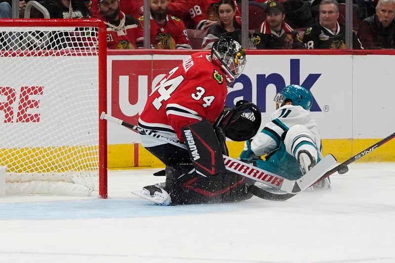 Oct 17, 2024; Chicago, Illinois, USA; San Jose Sharks center Luke Kunin (11) skates in on Chicago Blackhawks goaltender Petr Mrazek (34) during the second period at United Center. Mandatory Credit: David Banks-Imagn Images