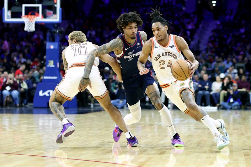 PHILADELPHIA, PENNSYLVANIA - JANUARY 22: Devin Vassell #24 of the San Antonio Spurs dribbles past Kelly Oubre Jr. #9 of the Philadelphia 76ers during the second quarter at the Wells Fargo Center on January 22, 2024 in Philadelphia, Pennsylvania. NOTE TO USER: User expressly acknowledges and agrees that, by downloading and or using this photograph, User is consenting to the terms and conditions of the Getty Images License Agreement. (Photo by Tim Nwachukwu/Getty Images)