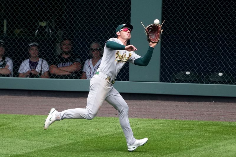 Jul 30, 2023; Denver, Colorado, USA; Oakland Athletics left fielder Brent Rooker (25) fields the ball in the fifth inning against the Colorado Rockies at Coors Field. Mandatory Credit: Ron Chenoy-USA TODAY Sports