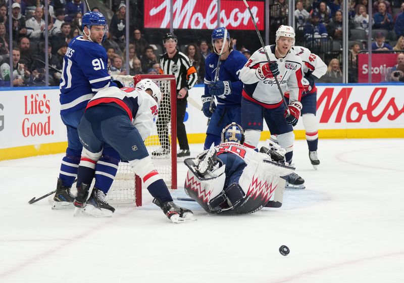 Dec 6, 2024; Toronto, Ontario, CAN; Toronto Maple Leafs center John Tavares (91) battles for the puck with Washington Capitals defenseman Martin Fehervary (42) in front of goaltender Charlie Lindgren (79) during the first period at Scotiabank Arena. Mandatory Credit: Nick Turchiaro-Imagn Images