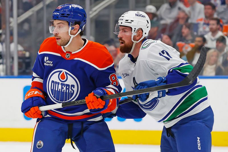 Oct 11, 2025; Edmonton, Alberta, CAN; Edmonton Oilers forward Andrew Mangiapane (88) and Vancouver Canucks defensemen Filip Hornek (17) look for a loose puck during the first period at Rogers Place. Mandatory Credit: Perry Nelson-Imagn Images