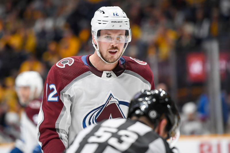 Nov 20, 2023; Nashville, Tennessee, USA; Colorado Avalanche center Ryan Johansen (12) mouths to linesman Bevan Mills (53) after not dropping the puck against the Nashville Predators during the second period at Bridgestone Arena. Mandatory Credit: Steve Roberts-USA TODAY Sports