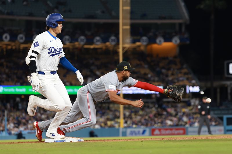 May 17, 2024; Los Angeles, California, USA;  Los Angeles Dodgers designated hitter Shohei Ohtani (17) is safe at the first base as Cincinnati Reds first baseman Jeimer Candelario (3) reaches for the ball during the seventh inning at Dodger Stadium. Mandatory Credit: Kiyoshi Mio-USA TODAY Sports