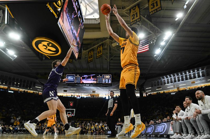 Feb 8, 2026; Iowa City, Iowa, USA; Iowa Hawkeyes forward Alvaro Folgueiras (7) shoots the ball over Northwestern Wildcats forward Nick Martinelli (2) during the second half at Carver-Hawkeye Arena. Mandatory Credit: Jeffrey Becker-Imagn Images