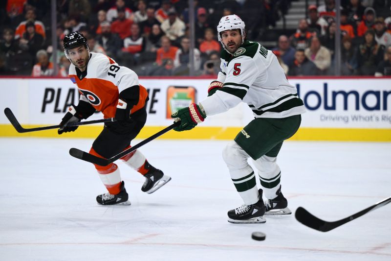 Oct 26, 2024; Philadelphia, Pennsylvania, USA; Minnesota Wild defenseman Jake Middleton (5) watches the puck against Philadelphia Flyers right wing Garnet Hathaway (19) in the second period at Wells Fargo Center. Mandatory Credit: Kyle Ross-Imagn Images