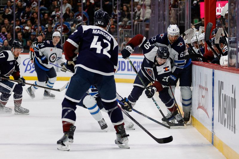 Jan 22, 2025; Denver, Colorado, USA; Colorado Avalanche center Ross Colton (20) and Winnipeg Jets right wing Nino Niederreiter (62) battle for the puck as defenseman Josh Manson (42) looks on in the third period at Ball Arena. Mandatory Credit: Isaiah J. Downing-Imagn Images
