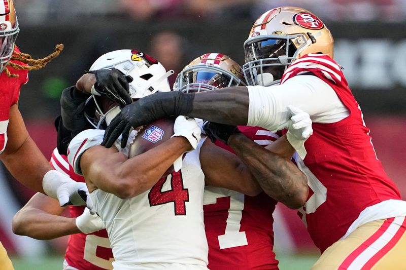 Arizona Cardinals wide receiver Rondale Moore (4) is tackled by San Francisco 49ers defenders during the first half of an NFL football game Sunday, Dec. 17, 2023, in Glendale, Ariz. (AP Photo/Matt York)