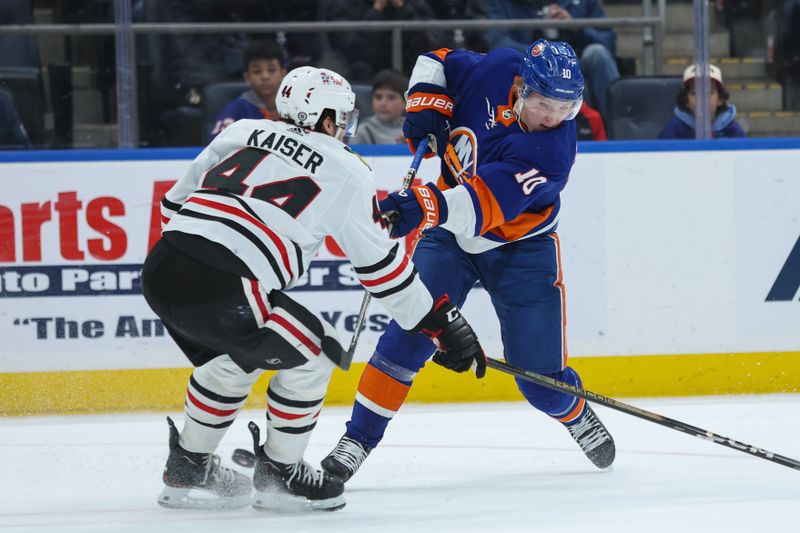 Apr 2, 2024; Elmont, New York, USA; New York Islanders right wing Simon Holmstrom (10) takes a shot while Chicago Blackhawks defenseman Wyatt Kaiser (44) pressures during the second period at UBS Arena. Mandatory Credit: Thomas Salus-USA TODAY Sports