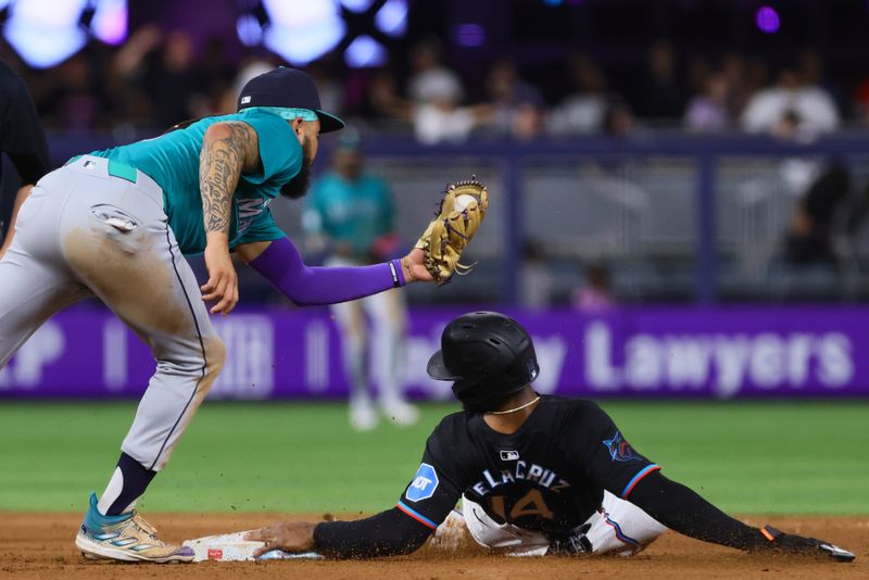 Jun 21, 2024; Miami, Florida, USA; Miami Marlins left fielder Bryan De La Cruz (14) steals second base against Seattle Mariners shortstop J.P. Crawford (3) during the ninth inning at loanDepot Park. Mandatory Credit: Sam Navarro-USA TODAY Sports