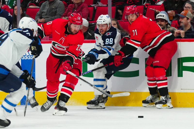 Mar 2, 2024; Raleigh, North Carolina, USA; Carolina Hurricanes right wing Stefan Noesen (23) and right wing Jesper Fast (71) battle for the puck against Winnipeg Jets defenseman Nate Schmidt (88) during the first period at PNC Arena. Mandatory Credit: James Guillory-USA TODAY Sports