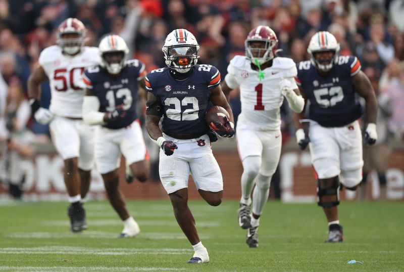 Nov 25, 2023; Auburn, Alabama, USA; Auburn Tigers running back Damari Alston (22) breaks free of Alabama Crimson Tide defenders during the second quarter at Jordan-Hare Stadium. Mandatory Credit: John Reed-USA TODAY Sports