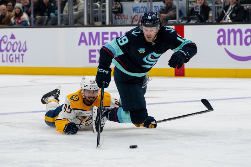 Nov 20, 2024; Seattle, Washington, USA;  Seattle Kraken forward Jared McCann (19) is tripped by Nashville Predators defenseman Alexandre Carrier (45) during the second period at Climate Pledge Arena. Mandatory Credit: Stephen Brashear-Imagn Images