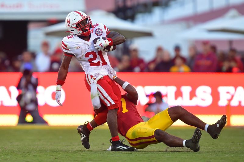 Nov 16, 2024; Los Angeles, California, USA; Nebraska Cornhuskers running back Emmett Johnson (21) is brought down by Southern California Trojans safety Kamari Ramsey (7) during the second half at the Los Angeles Memorial Coliseum. Mandatory Credit: Gary A. Vasquez-Imagn Images