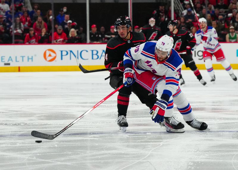 Mar 12, 2024; Raleigh, North Carolina, USA; New York Rangers defenseman K'Andre Miller (79) skates with the puck against Carolina Hurricanes center Seth Jarvis (24) during the first period at PNC Arena. Mandatory Credit: James Guillory-USA TODAY Sports