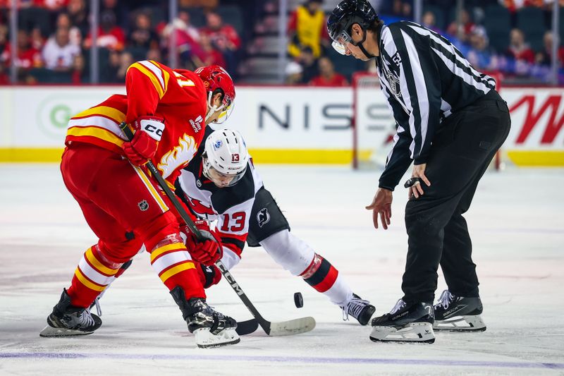 Jan 19, 2026; Calgary, Alberta, CAN; New Jersey Devils center Nico Hischier (13) and Calgary Flames center Mikael Backlund (11) face off for the puck during the first period at Scotiabank Saddledome. Mandatory Credit: Sergei Belski-Imagn Images