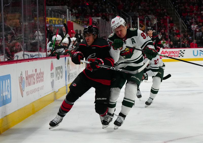 Jan 21, 2024; Raleigh, North Carolina, USA; Minnesota Wild left wing Kirill Kaprizov (97) checks Carolina Hurricanes left wing Teuvo Teravainen (86) during the first period at PNC Arena. Mandatory Credit: James Guillory-USA TODAY Sports