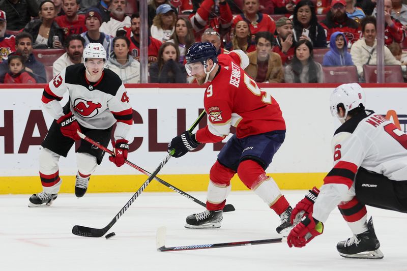 Jan 13, 2024; Sunrise, Florida, USA; Florida Panthers center Sam Bennett (9) moves the puck as New Jersey Devils defenseman Luke Hughes (43) and defenseman John Marino (6) defend during the second period at Amerant Bank Arena. Mandatory Credit: Sam Navarro-USA TODAY Sports