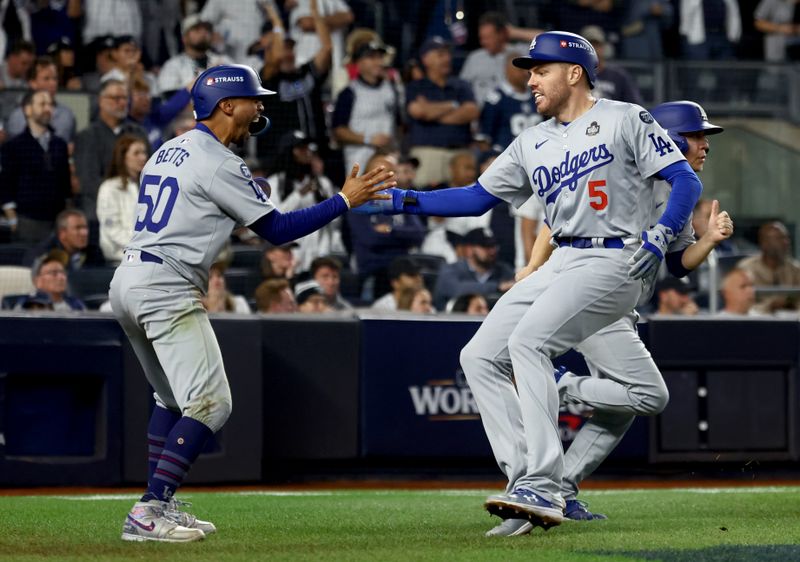 Oct 30, 2024; New York, New York, USA; Los Angeles Dodgers first baseman Freddie Freeman (5) celebrates with  shortstop Mookie Betts (50) after they scored during the fifth inning against the New York Yankees in game five of the 2024 MLB World Series at Yankee Stadium. Mandatory Credit: Vincent Carchietta-Imagn Images