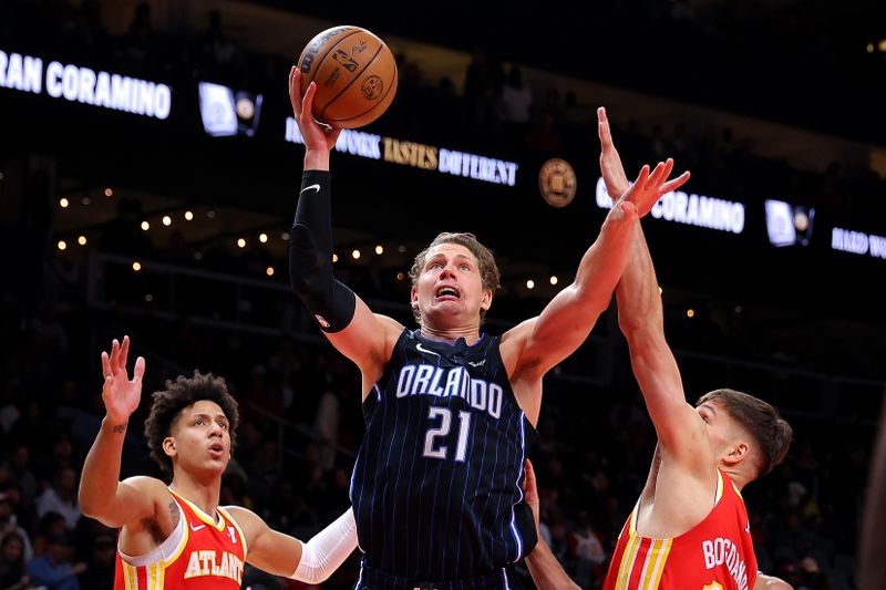 ATLANTA, GEORGIA - FEBRUARY 25:  Moritz Wagner #21 of the Orlando Magic drives against Bogdan Bogdanovic #13 and Jalen Johnson #1 of the Atlanta Hawks during the first quarter at State Farm Arena on February 25, 2024 in Atlanta, Georgia.  NOTE TO USER: User expressly acknowledges and agrees that, by downloading and/or using this photograph, user is consenting to the terms and conditions of the Getty Images License Agreement.  (Photo by Kevin C. Cox/Getty Images)